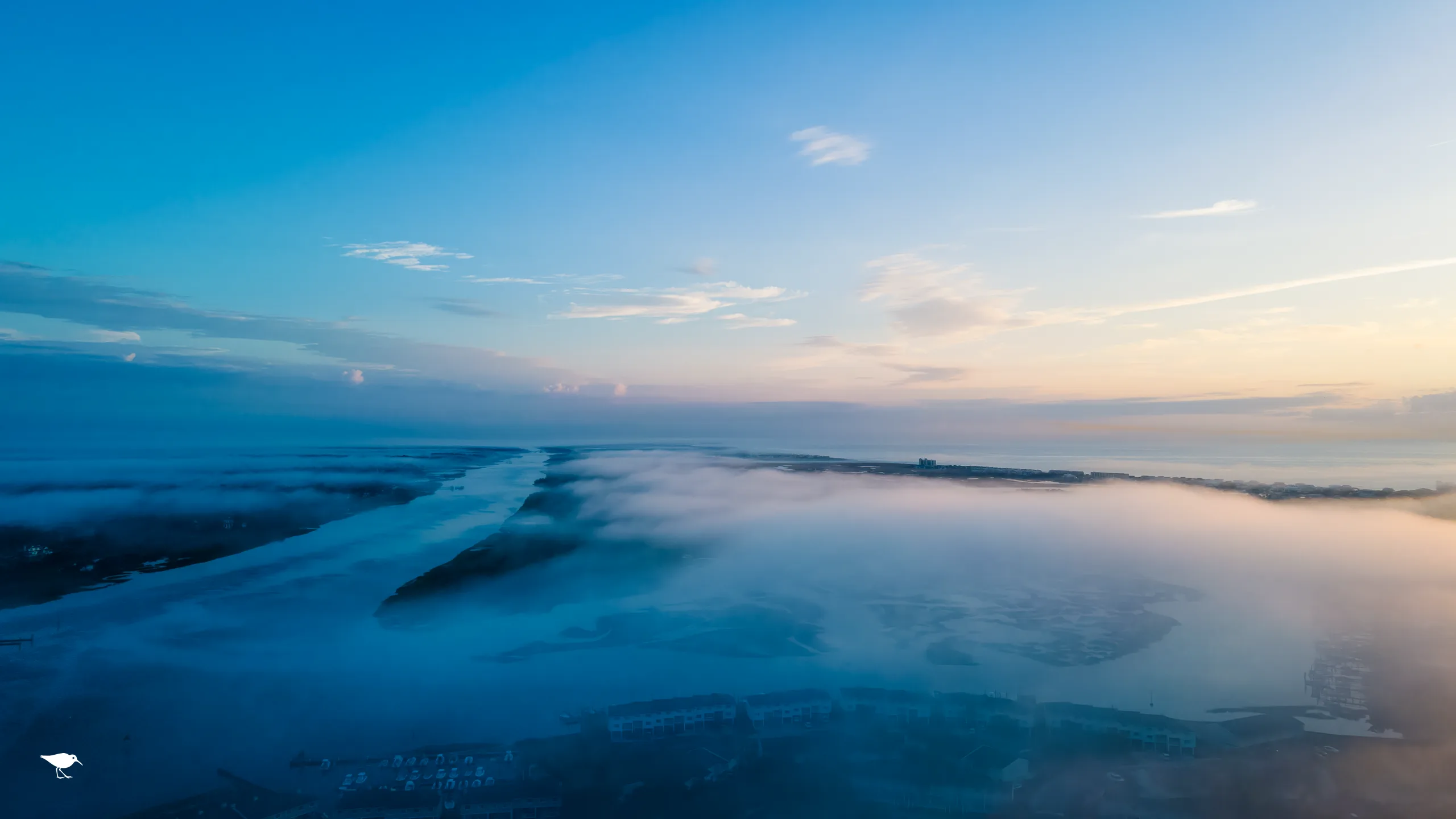 Aerial view of fog rolling over a coastal marsh at sunrise