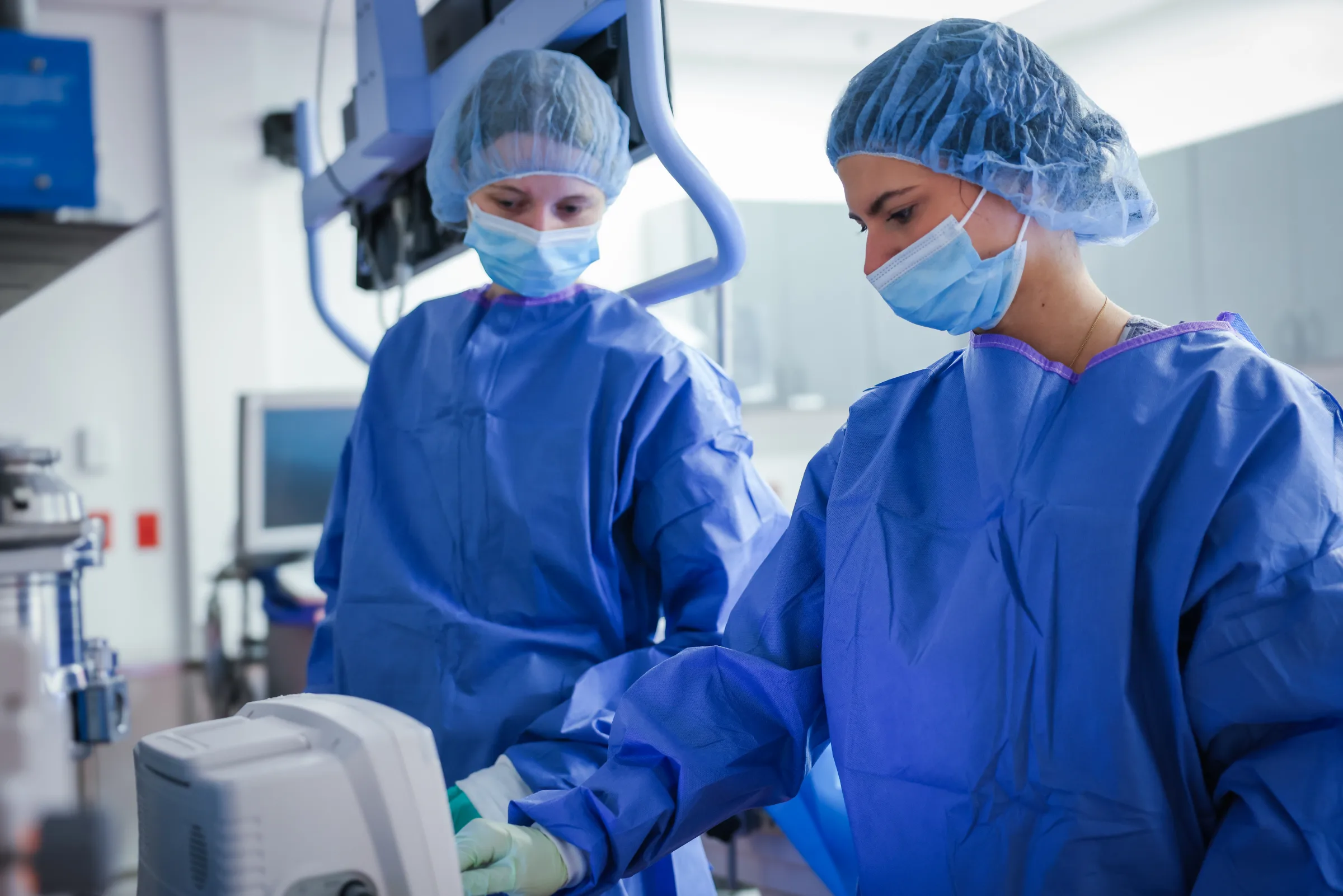 Two gowned Synchrony Labs clinicians operating imaging equipment in the procedure suite
