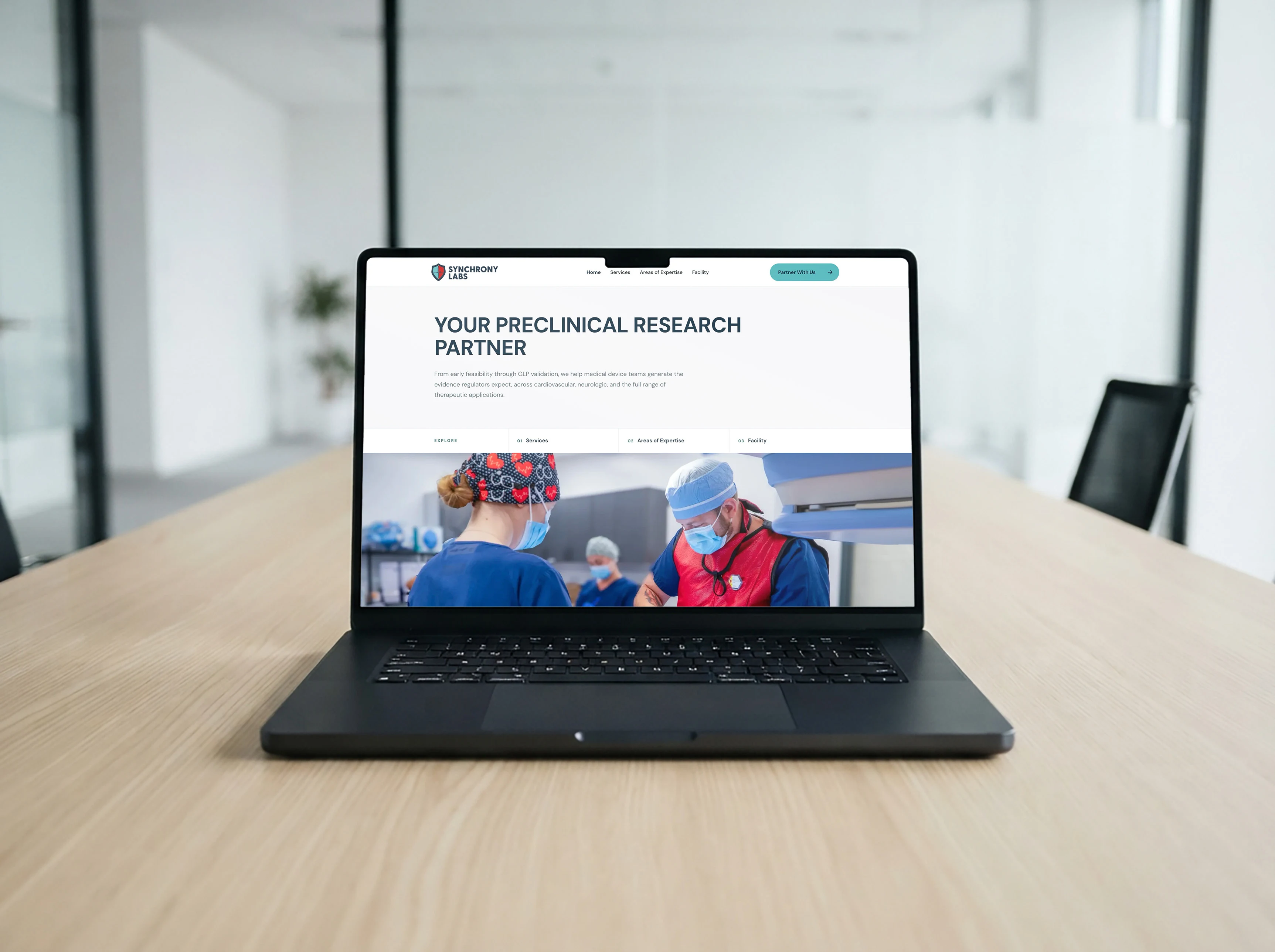 The Synchrony Labs homepage open on a laptop in their conference room